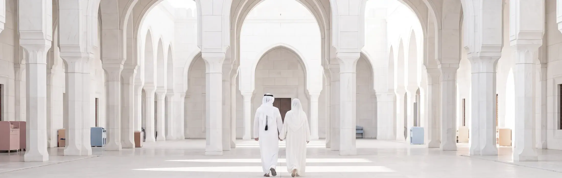 A couple walking together down a colonnade of white marble mosque arches